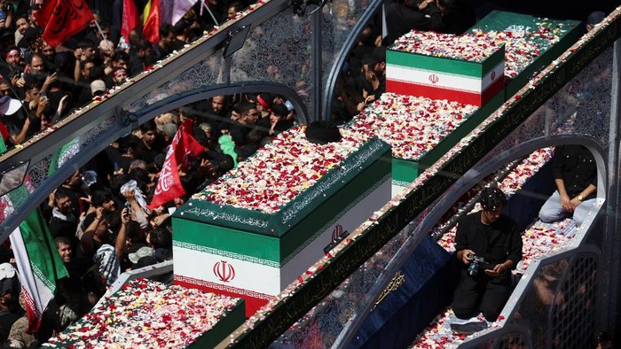 Peti jenazah Khamenei yang diselimuti bendera Iran diarak menggunakan kendaraan khusus bersama peti jenazah sejumlah anggota keluarganya yang juga tewas dalam serangan tersebut. Prosesi berlangsung dari Lapangan Enghelab menuju Bandara Mehrabad. (IDNVoice/Reuters-Murad Sezer)
