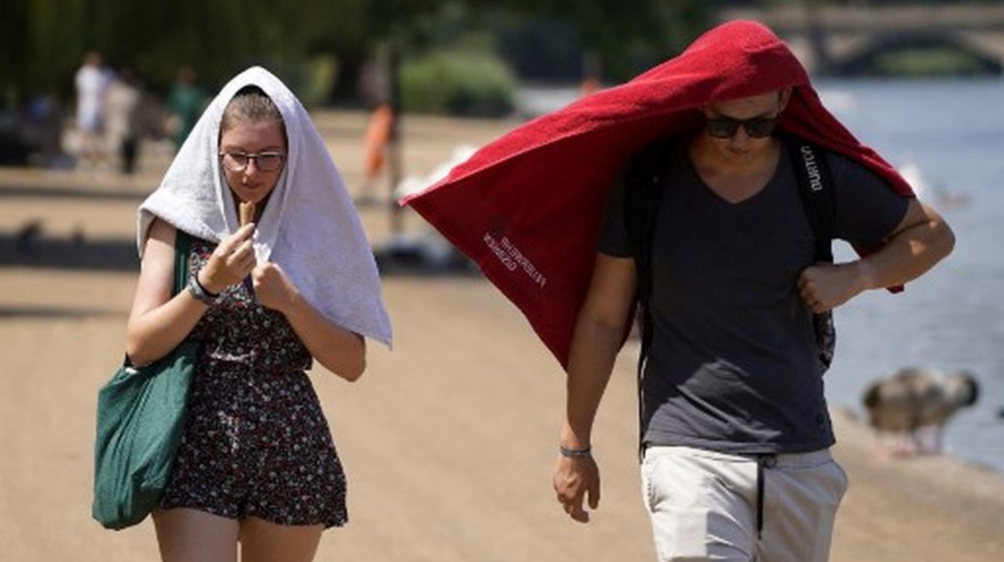 Ilustrasi: Orang-orang menutupi kepala mereka untuk berlindung dari matahari saat mereka berjalan melewati danau Serpentine di Hyde Park, London barat, pada 19 Juli 2022 saat negara itu mengalami gelombang panas yang ekstrem. (IDNVoice/AFP Photo)